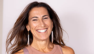 Beautiful brunette woman in bold jewelry smiling joyfully.