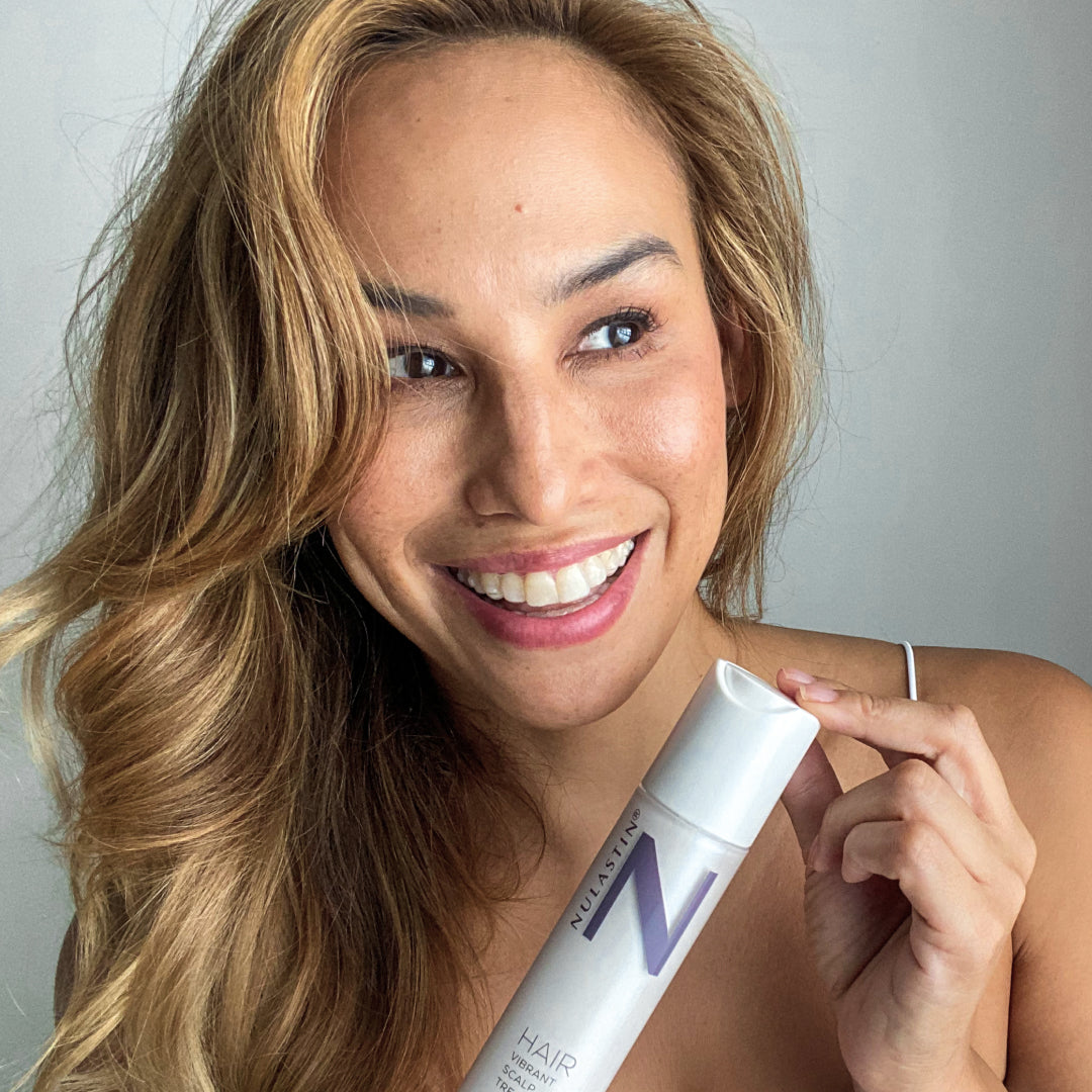 Content creator holding Vibrant Scalp Treatment while smiling
