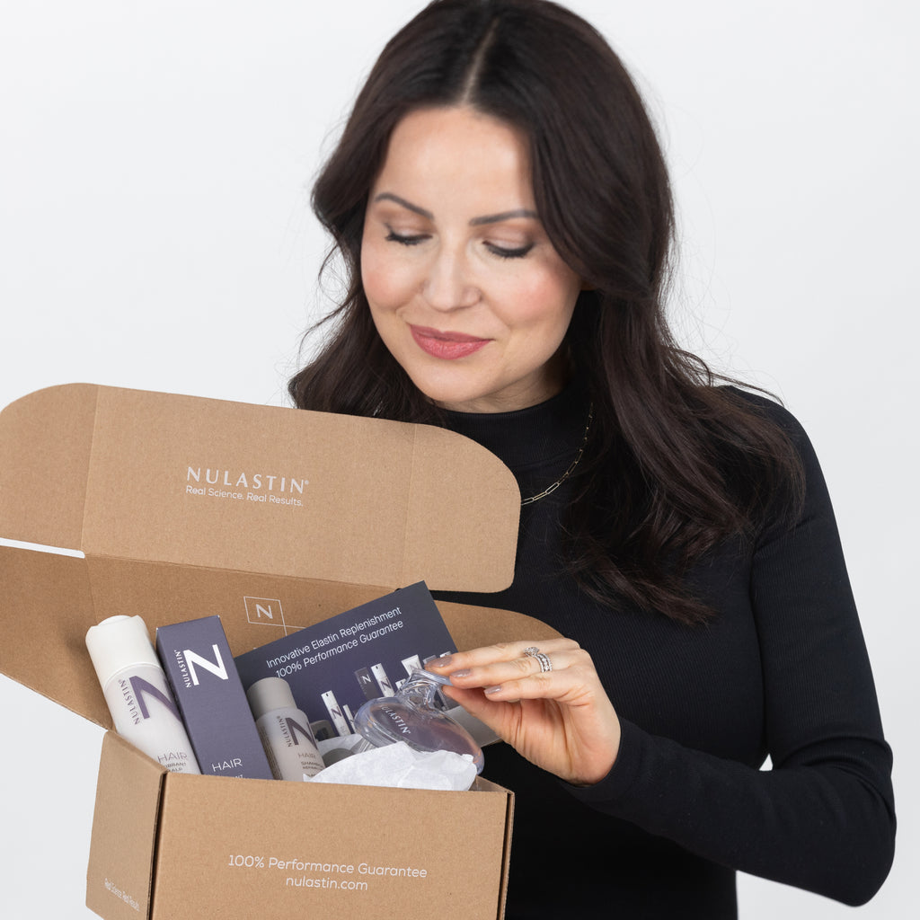 A brunette opening a box of Nulastin products she ordered with her Nulastin E-Gift Card