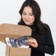 A brunette opening a box of Nulastin products she ordered with her Nulastin E-Gift Card