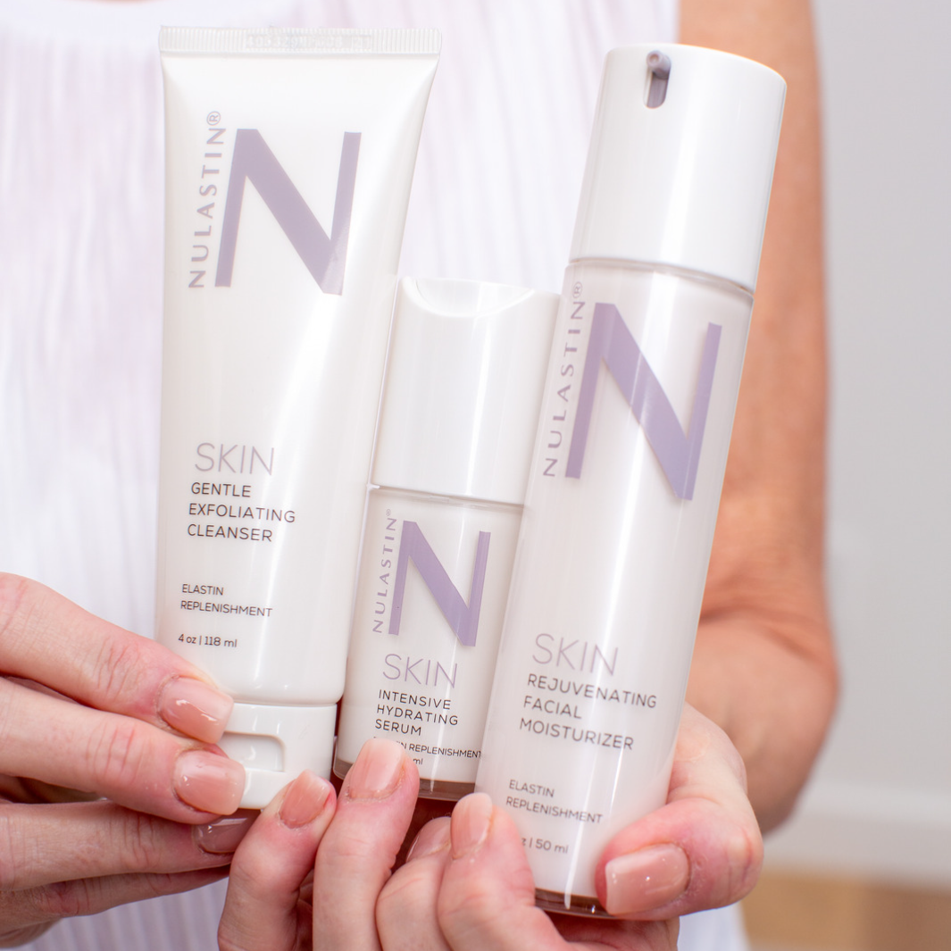 Hands holding three NULASTIN skincare bottles from 3 step skincare routine