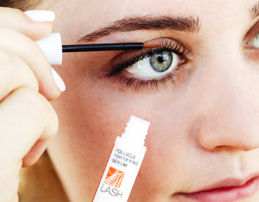 Close-up of lash serum wand applying NULASTIN Follicle Fortifying Serum to upper eyelashes