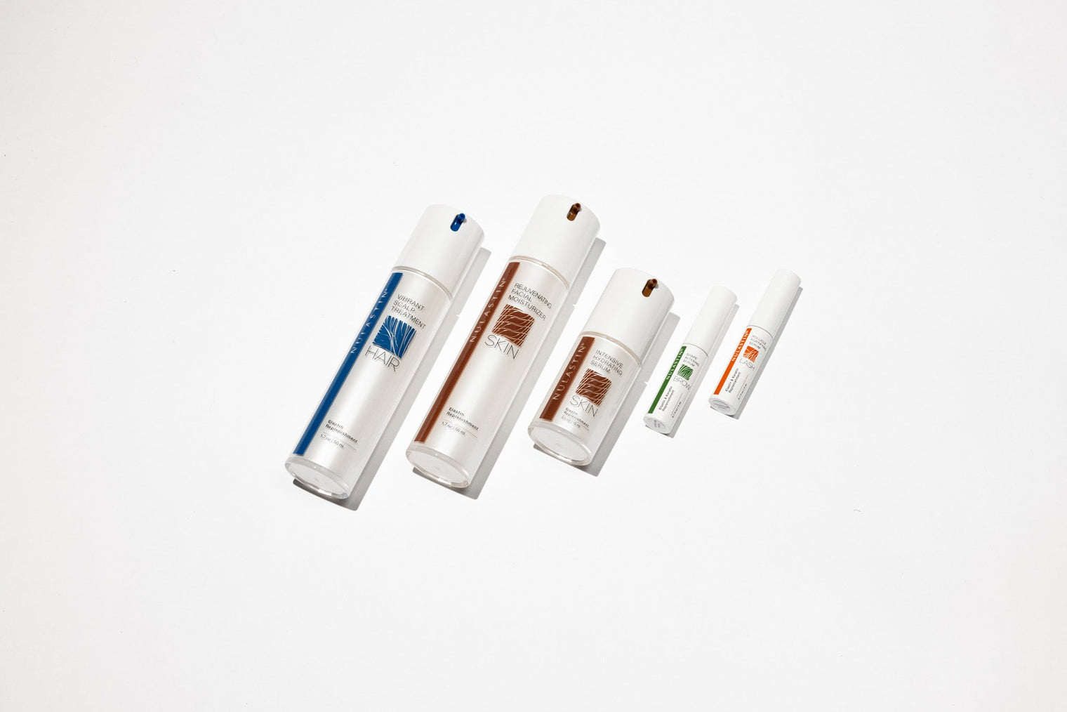 Top-down angled view of NULASTIN serums and treatment tubes labeled HAIR and SKIN with colored accents on white background