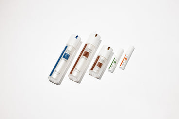 Top-down angled view of NULASTIN serums and treatment tubes labeled HAIR and SKIN with colored accents on white background