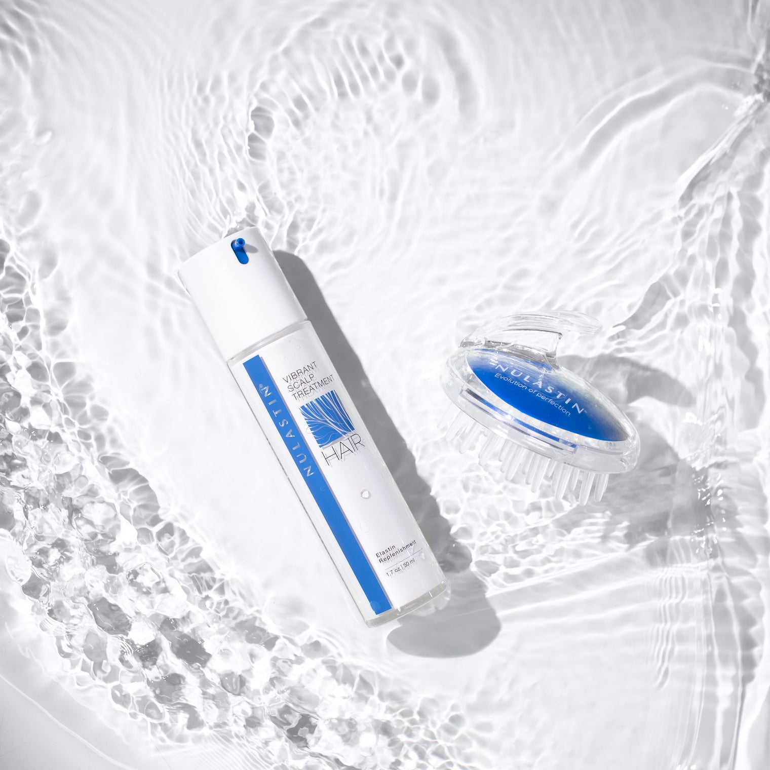 Top-down view of NULASTIN Vibrant Scalp Treatment bottle and clear blue scalp massager showing pump and bristles on rippling water background
