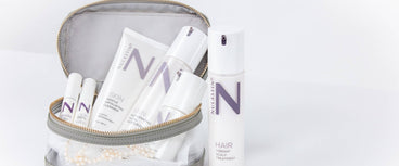 Front view of NULASTIN skincare and serum bottles in a clear travel pouch showcasing product packaging on white background
