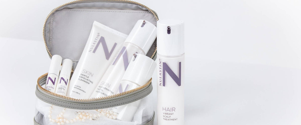 Front of NULASTIN clear travel pouch with skincare and hair treatment products on white background