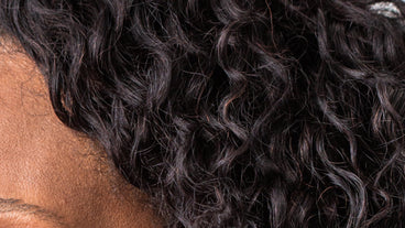 Person's dark curly hair showing tight curls and natural texture at the temple