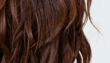 Close-up of wavy medium-brown hair showing smooth texture and shine against a light background