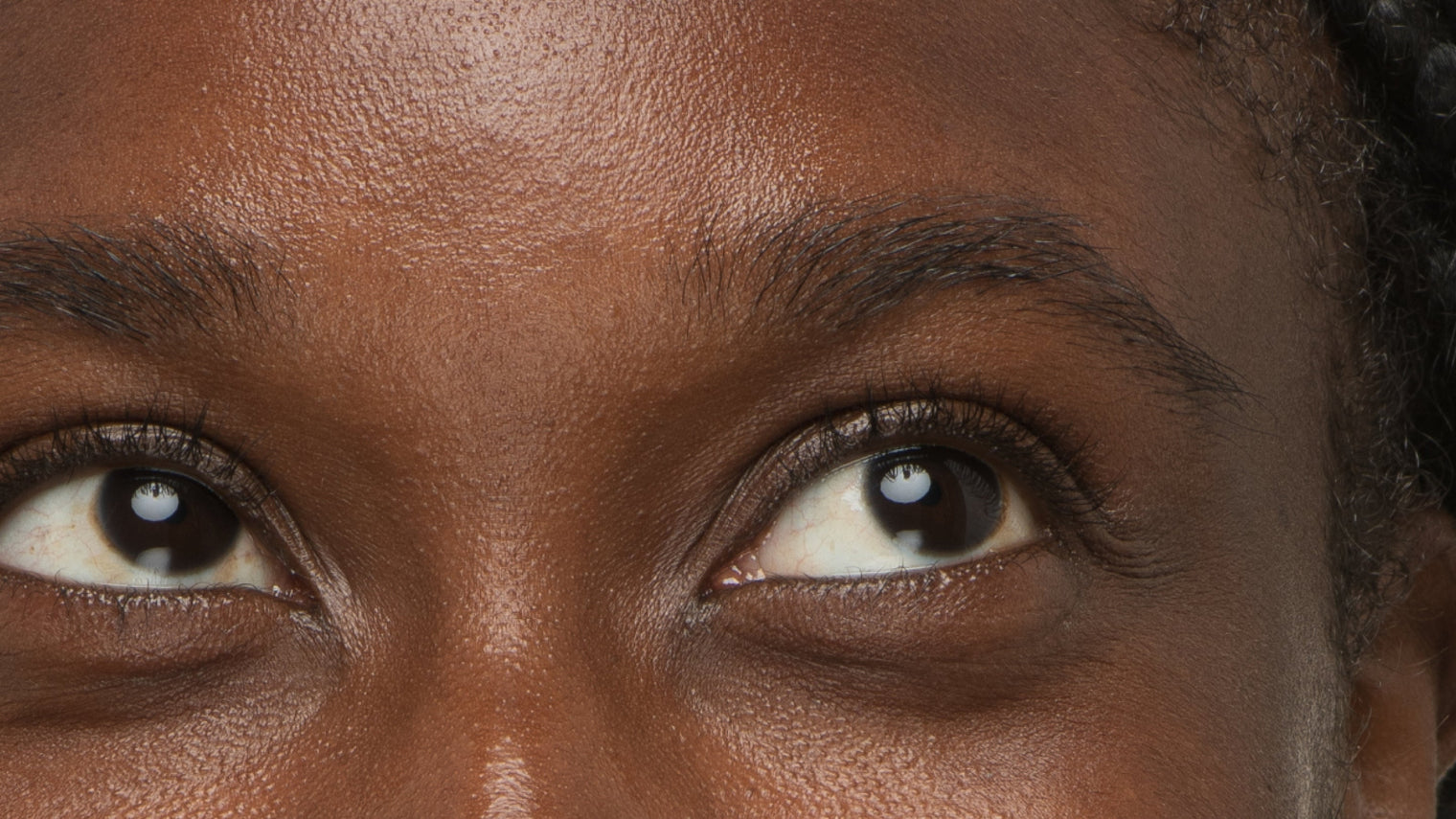 Close-up of a person's eyes looking upward showing visibly longer, fuller lashes and natural brows
