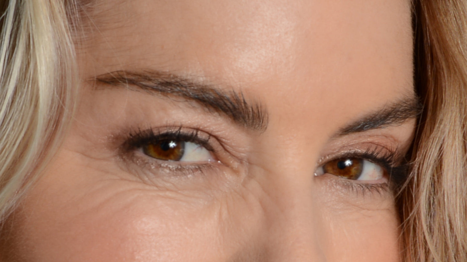 Close-up of a woman's eyes and brows showing visibly fuller eyebrow hairs