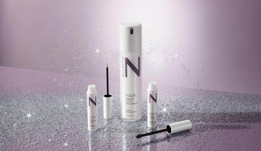 Front view of NULASTIN hair, lash, and brow serums showcasing applicators and product branding on a glittery purple background