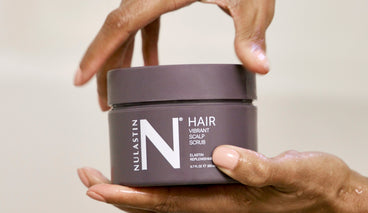Close-up front view of Vibrant Scalp Scrub jar 6.7 fl oz showcasing label and screw-top lid held in wet hands against a neutral background