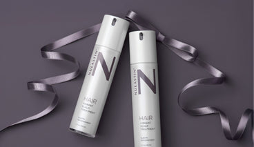 Angled flat-lay of two NULASTIN Hair Vibrant Scalp Treatment pump bottles showing N logo with purple ribbon on mauve background