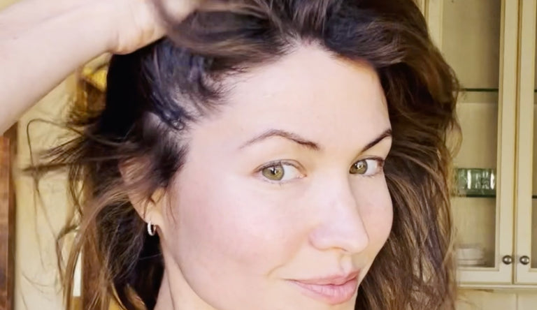 Beautiful brunette woman runs her fingers through her hair looking straight into the camera with piercing green eyes.