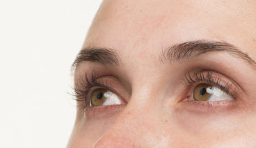 Close up of a woman with long lashes looking up. 