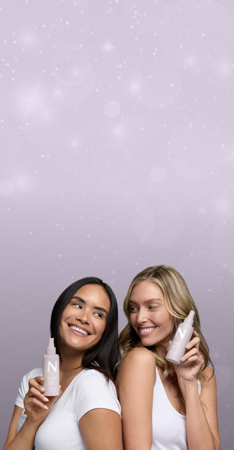 Two women smiling and holding NULASTIN HAIR treatments against a lavender sparkling background