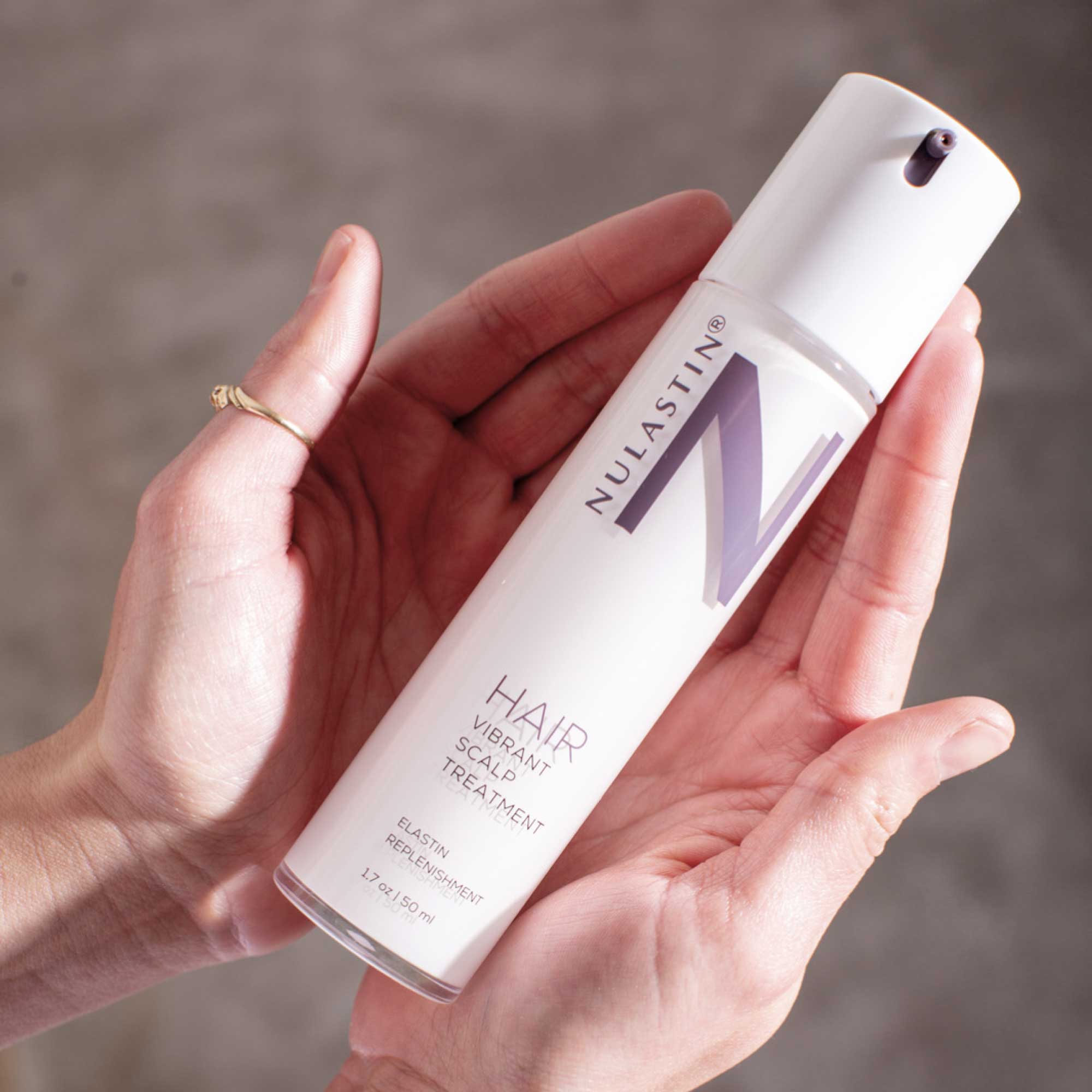 Hands cradling our award winning, clinically proven Vibrant Scalp Treatment