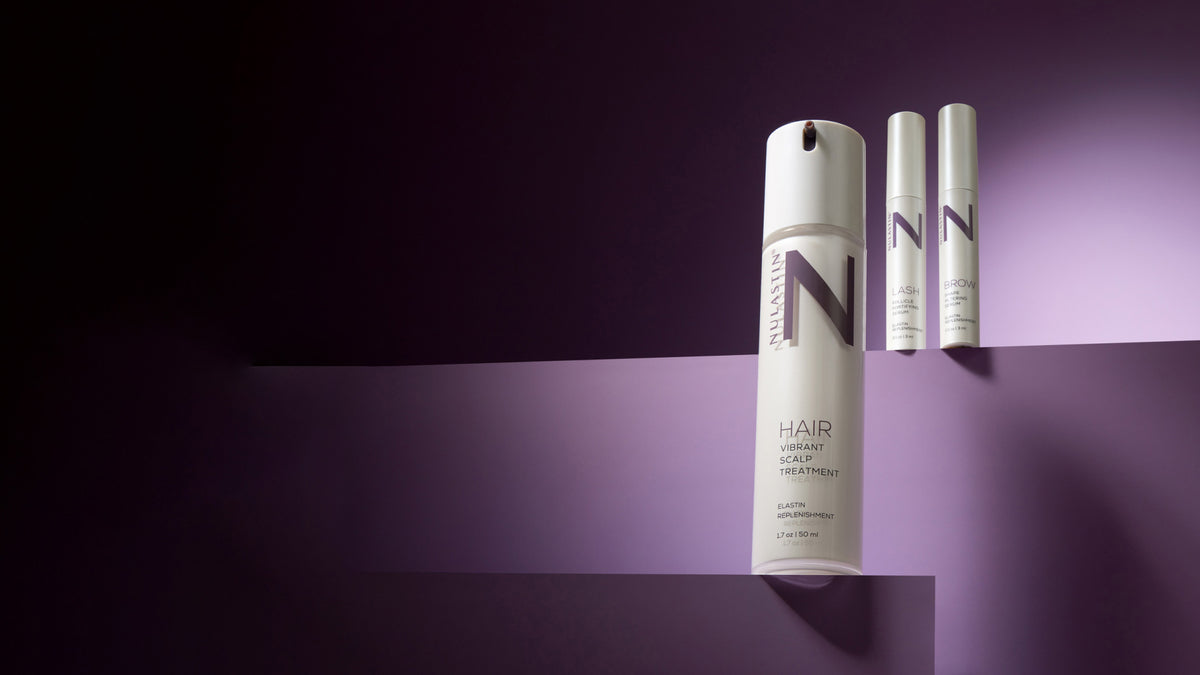 NULASTIN hair, lash and brow products on a dark purple set