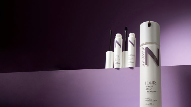 Nulastin lash and brow serums and vibrant scalp treatment on a dramatic ledge with purple background