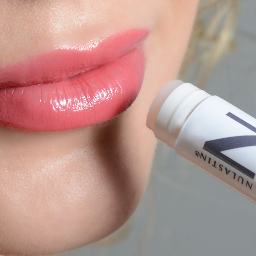 A close up of a woman holding Natural Lip Balm near her lips 