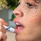 A women with freckles applying Natural Lip Balm to her lips