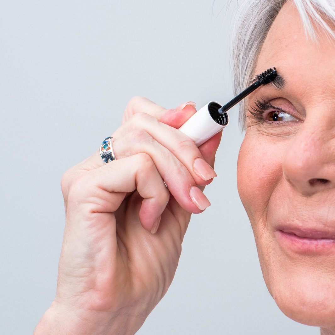 Woman applying NULASTIN brow shape serum to eyebrows