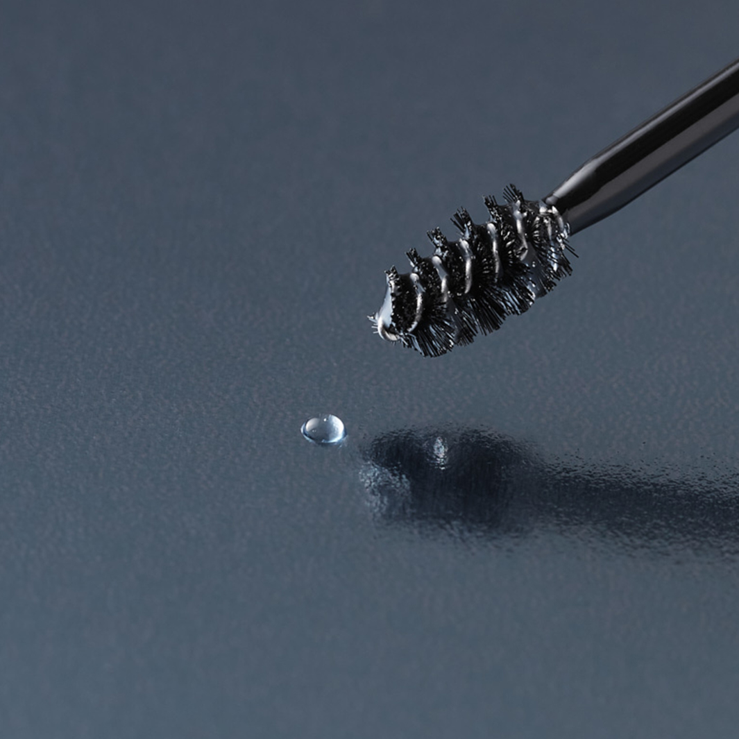 NULASTIN brow shape serum applicator and drop of serum on blue reflective surface