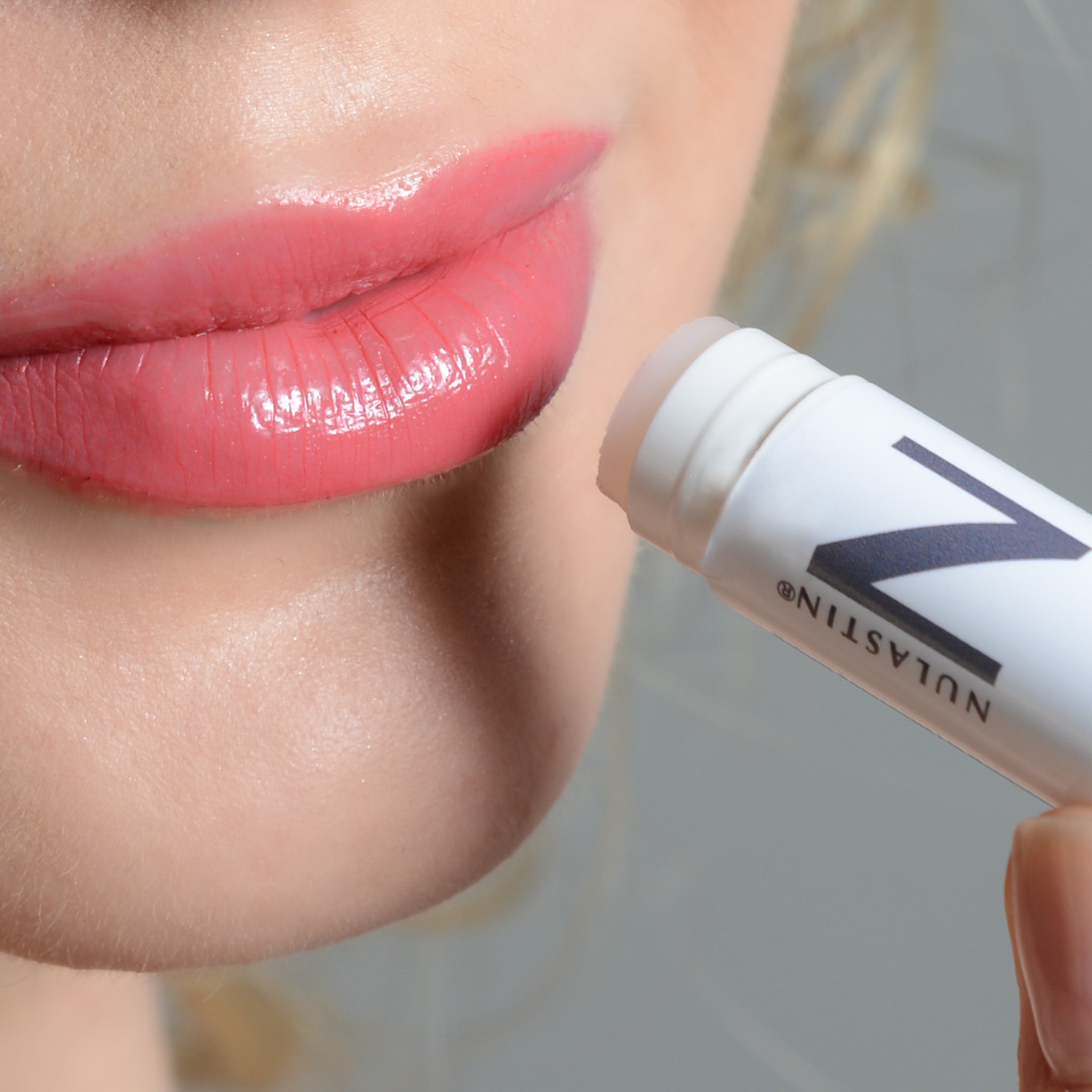Close up of woman applying NULASTIN lip balm to plump lips