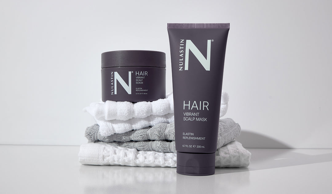 Front of NULASTIN Vibrant Scalp Mask tube and Vibrant Scalp Scrub jar on stacked white and gray towels