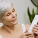 Mature looking woman holding a tube of Gentle Exfoliating Cleanser 