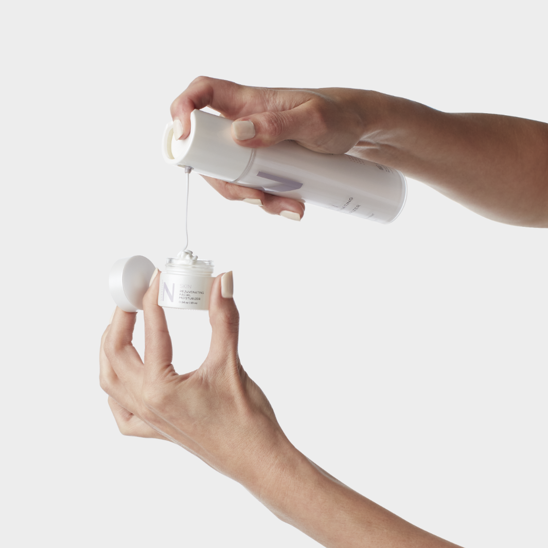 Hands pumping hair product from large bottle into small container against white background 